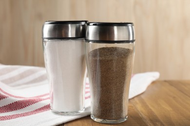 Photo of Salt and pepper shakers on wooden table, closeup