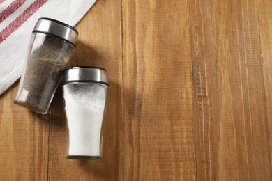 Photo of Salt and pepper shakers on wooden table, flat lay. Space for text