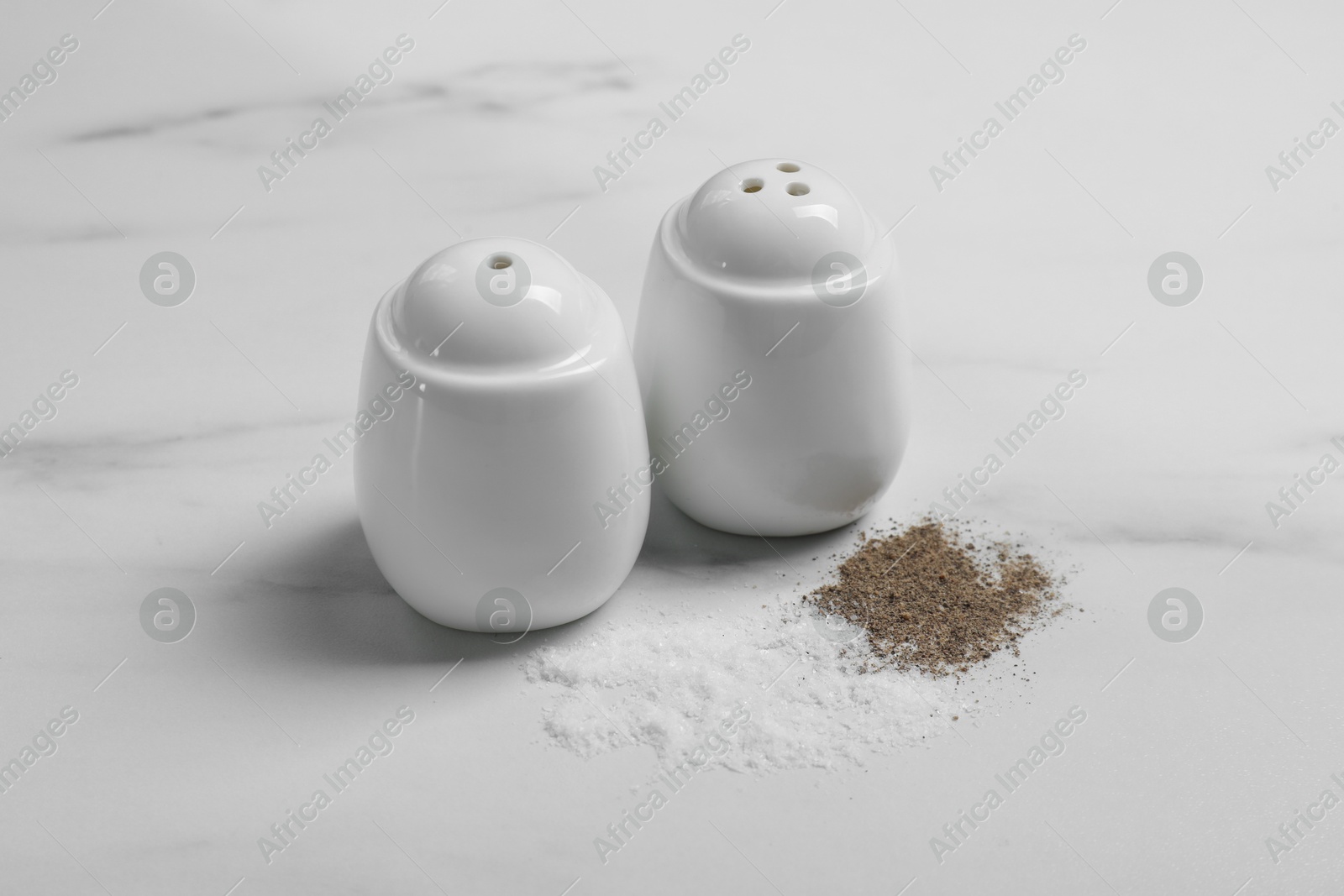 Photo of Salt and pepper shakers on white marble table