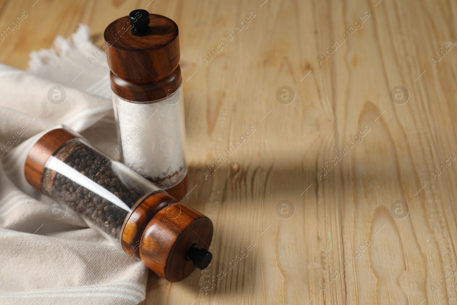 Photo of Salt and pepper shakers on wooden table. Space for text