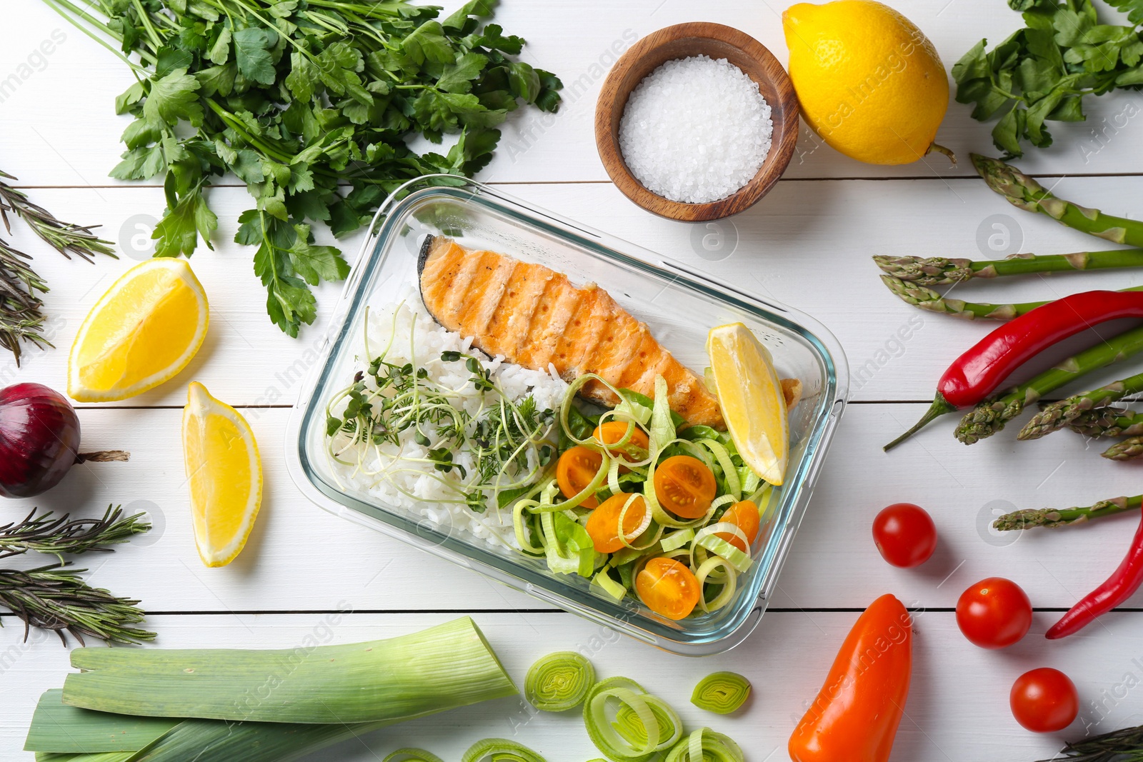 Photo of Healthy meal. Salmon, rice and salad in container near other products on white wooden table, flat lay