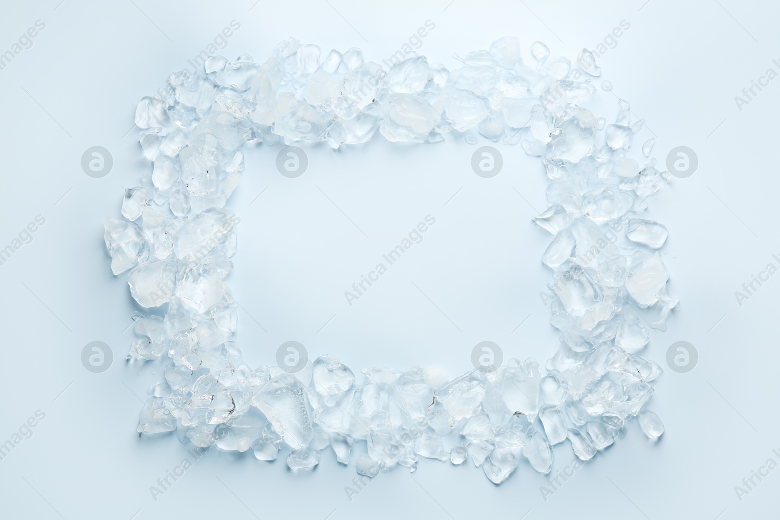 Photo of Frame of crushed ice on light blue background, top view. Space for text