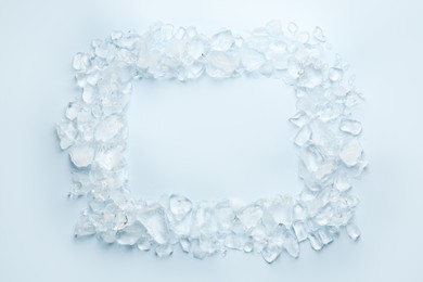 Frame of crushed ice on light blue background, top view. Space for text