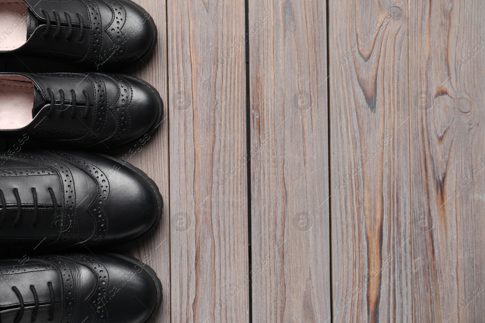 Photo of Big and small shoes on wooden table, top view. Space for text