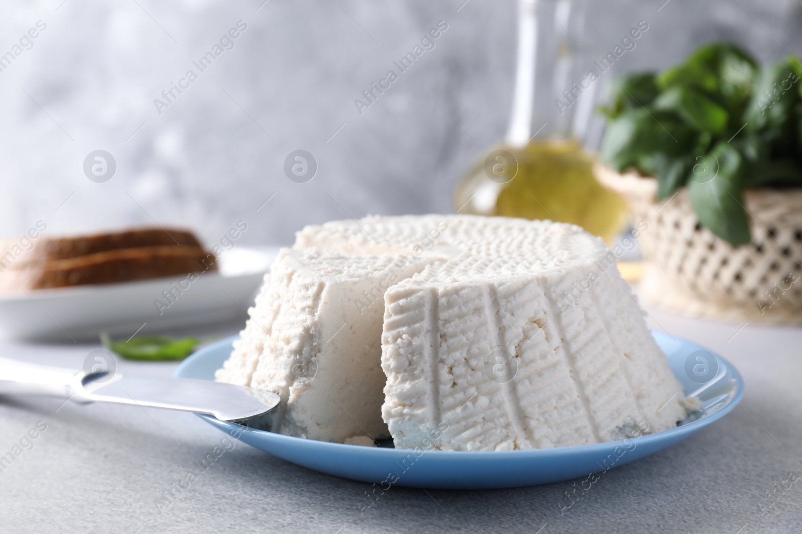 Photo of Tasty ricotta (cream cheese) and knife on grey table, closeup