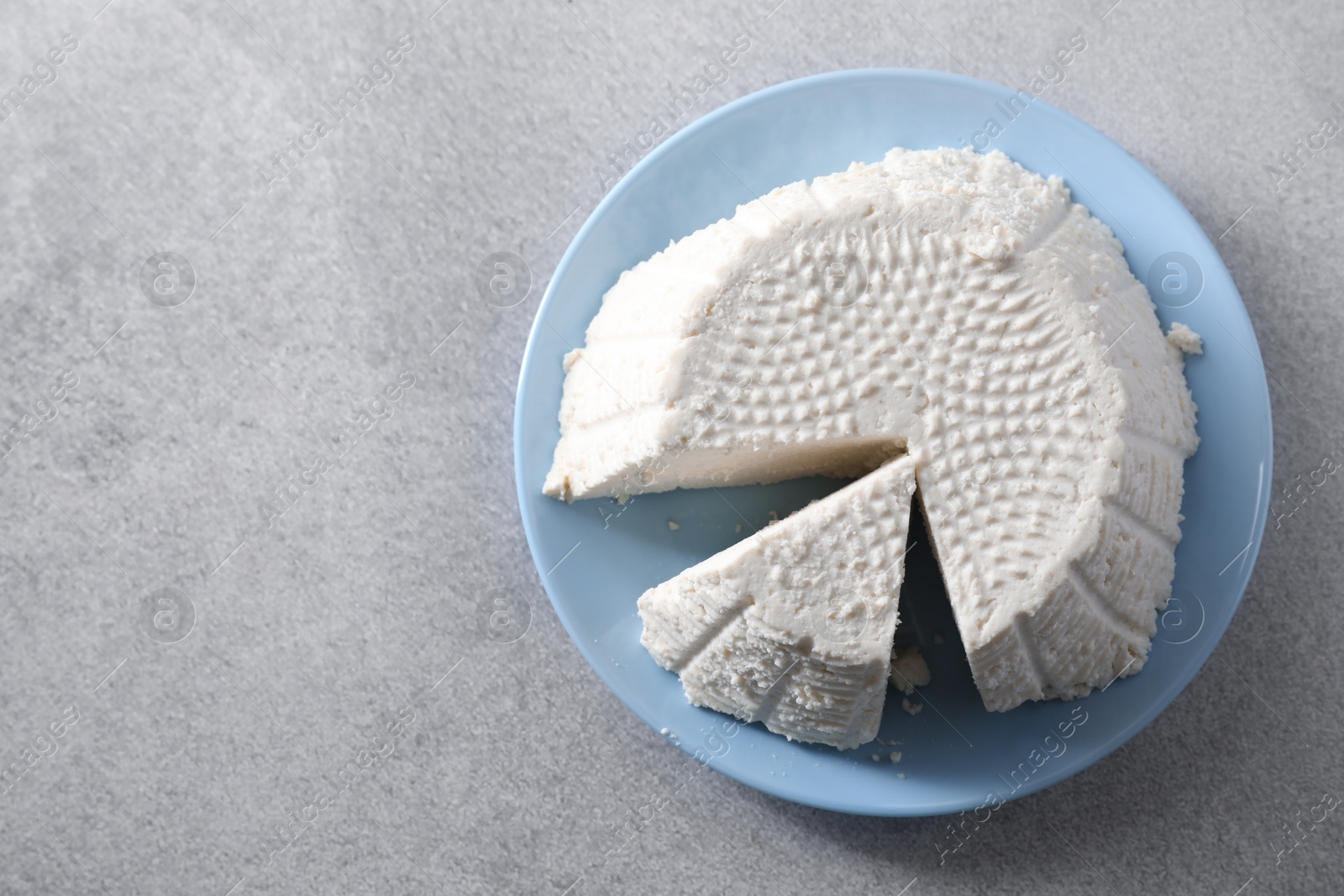 Photo of Tasty ricotta (cream cheese) on grey table, top view. Space for text