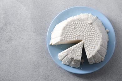 Photo of Tasty ricotta (cream cheese) on grey table, top view. Space for text