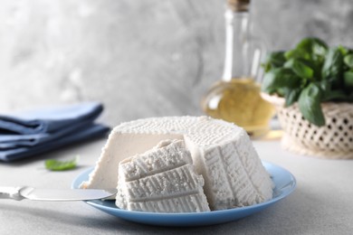 Tasty ricotta (cream cheese) and knife on grey table