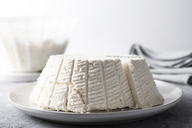 Photo of Tasty ricotta (cream cheese) on grey textured table, closeup