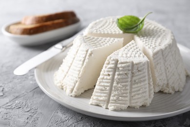 Tasty ricotta (cream cheese) and knife on grey textured table, closeup