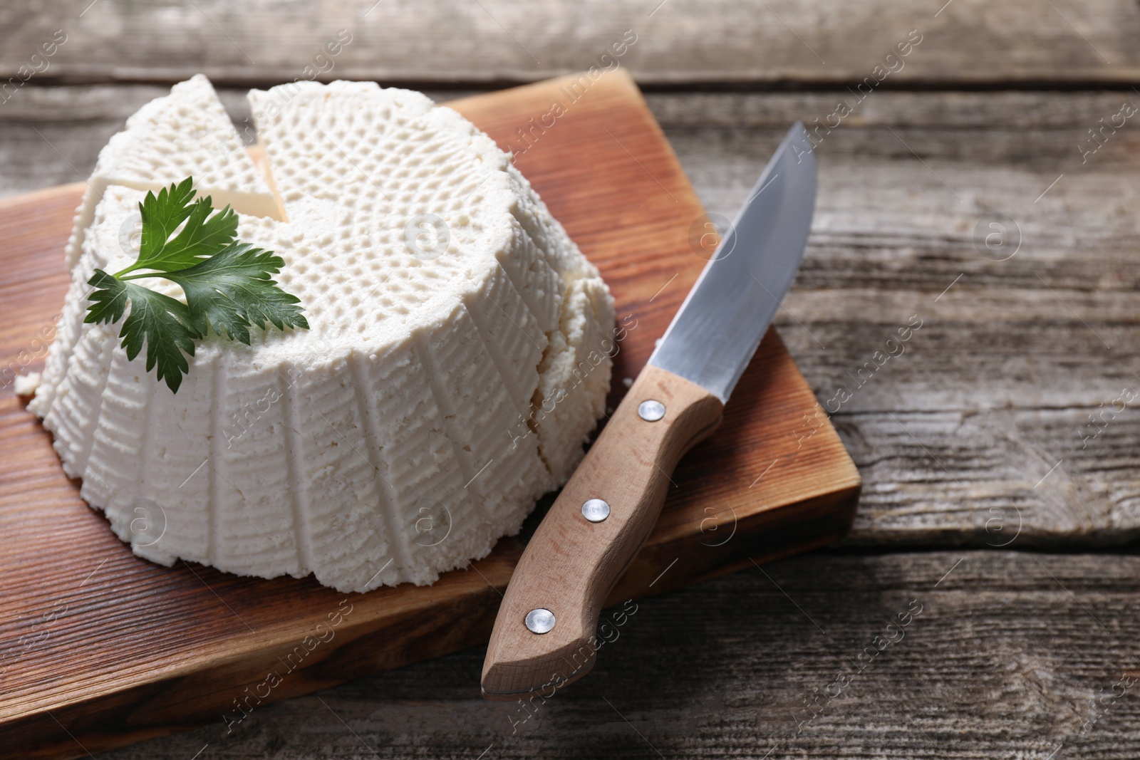 Photo of Tasty ricotta (cream cheese) and knife on wooden table