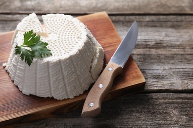 Tasty ricotta (cream cheese) and knife on wooden table