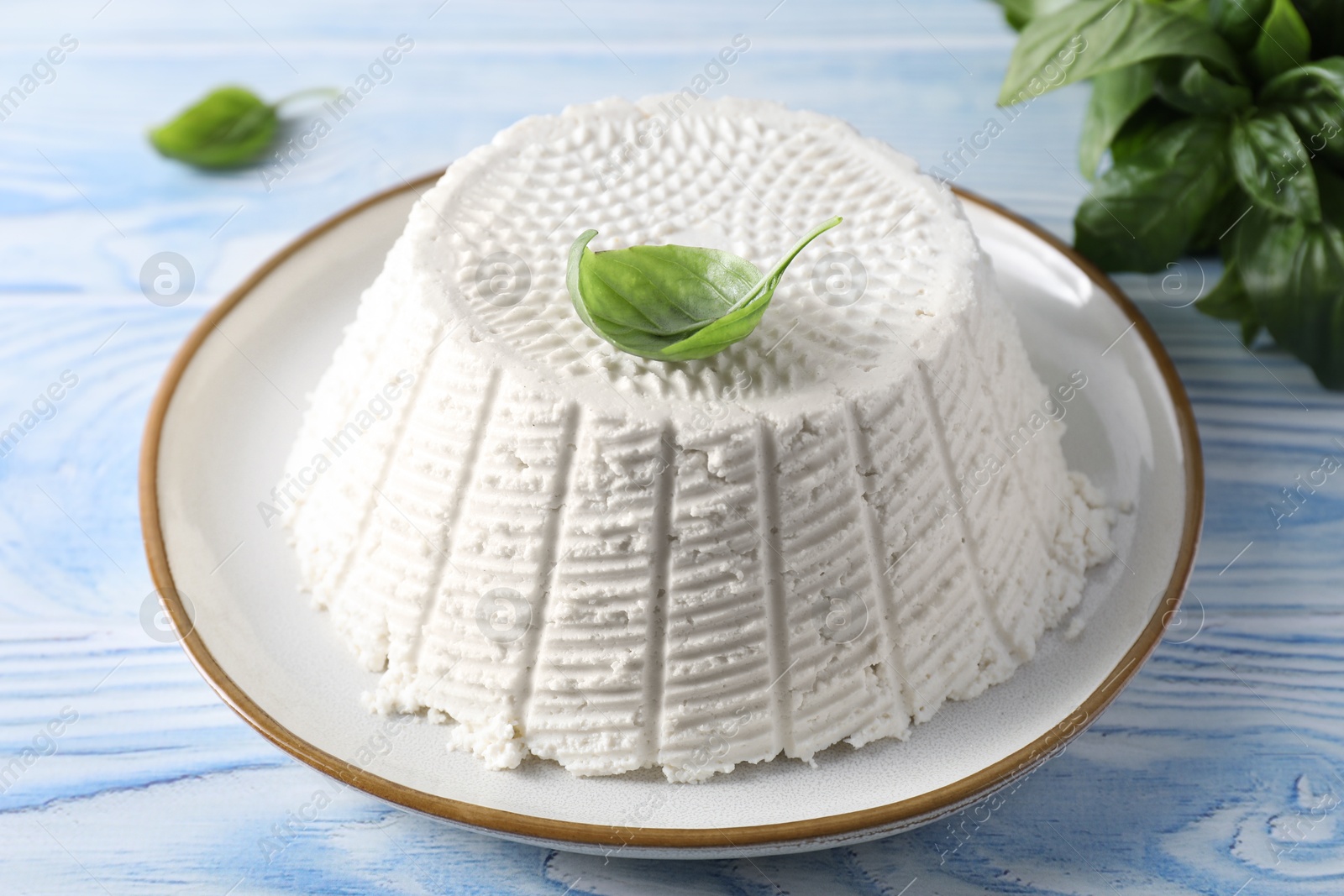 Photo of Tasty ricotta (cream cheese) on light blue wooden table