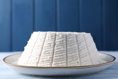 Photo of Tasty ricotta (cream cheese) on light blue wooden table, closeup