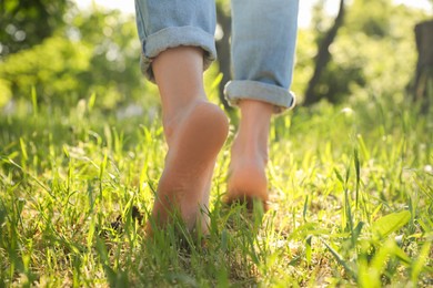 Woman walking barefoot on green grass outdoors, closeup