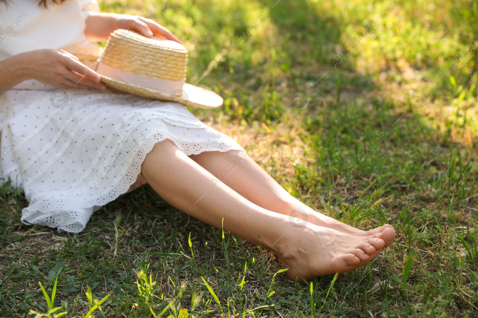 Photo of Woman sitting barefoot on green grass outdoors, closeup