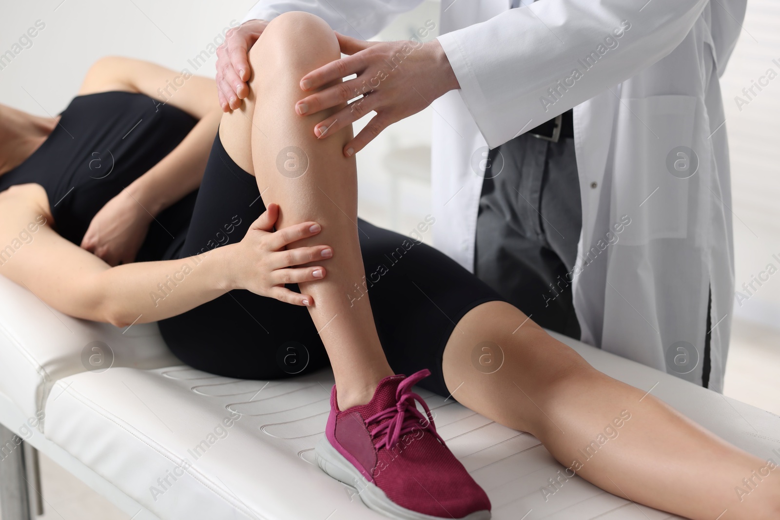 Photo of Sports injury. Doctor examining patient's knee in hospital, closeup