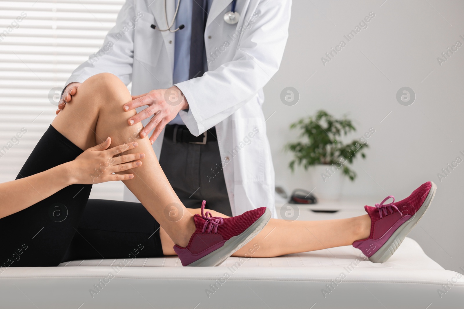 Photo of Sports injury. Doctor examining patient's knee in hospital, closeup