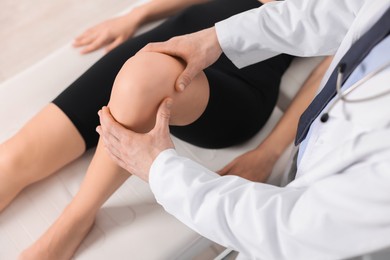 Sports injury. Doctor examining patient's knee in hospital, top view