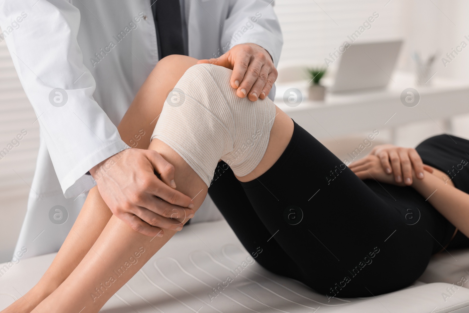 Photo of Sports injury. Doctor examining patient's knee in hospital, closeup