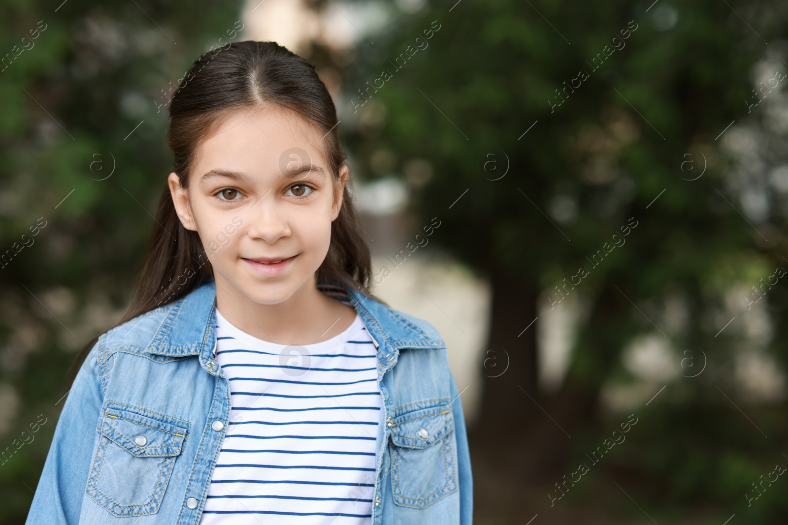 Photo of Portrait of cute little girl outdoors, space for text