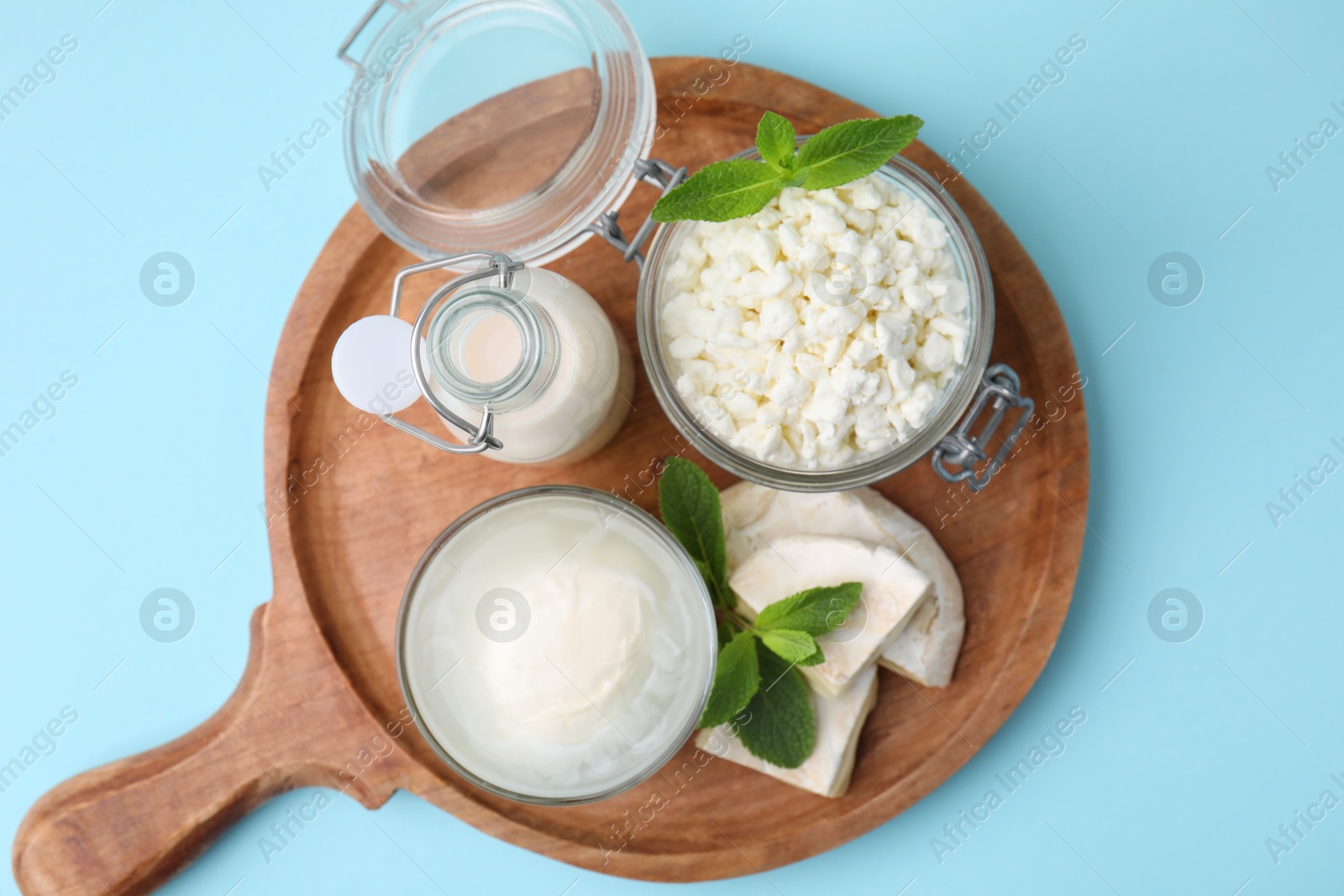 Photo of Different dairy products and mint on light blue background, top view