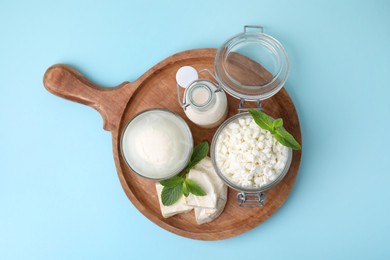 Photo of Different dairy products and mint on light blue background, top view