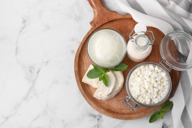 Photo of Different dairy products and mint on white marble table, top view. Space for text