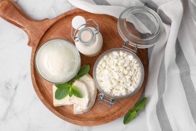 Photo of Different dairy products and mint on white marble table, top view