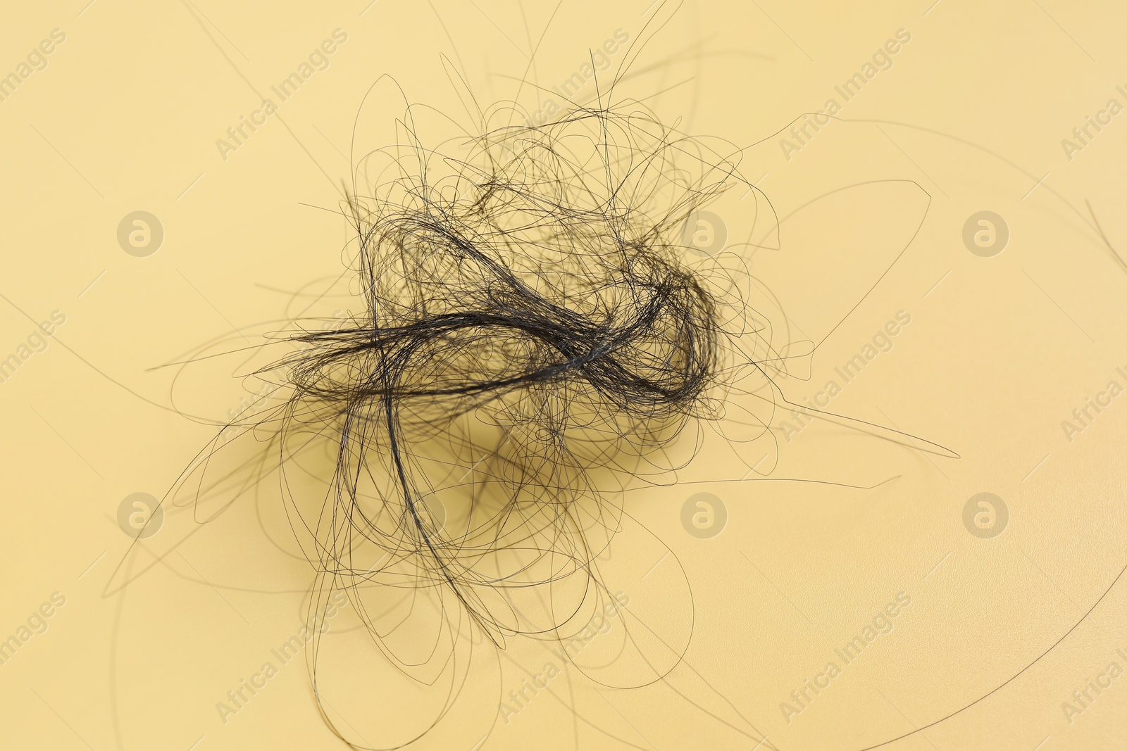 Photo of Pile of lost hair on yellow background