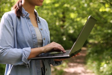 Photo of Forester with laptop working in forest, closeup