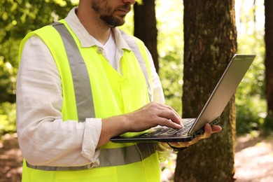 Photo of Forester with laptop working in forest, closeup
