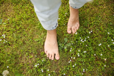 Photo of Woman walking barefoot on green grass outdoors, top view