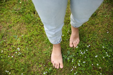 Photo of Woman walking barefoot on green grass outdoors, top view