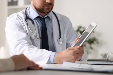 Professional doctor working with patient at white table in hospital, closeup