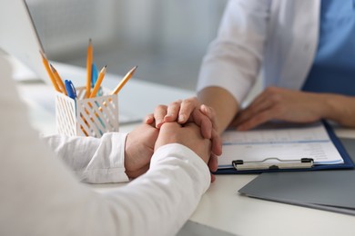 Professional doctor working with patient at white table in hospital, closeup