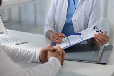 Photo of Professional doctor working with patient at white table in hospital, closeup