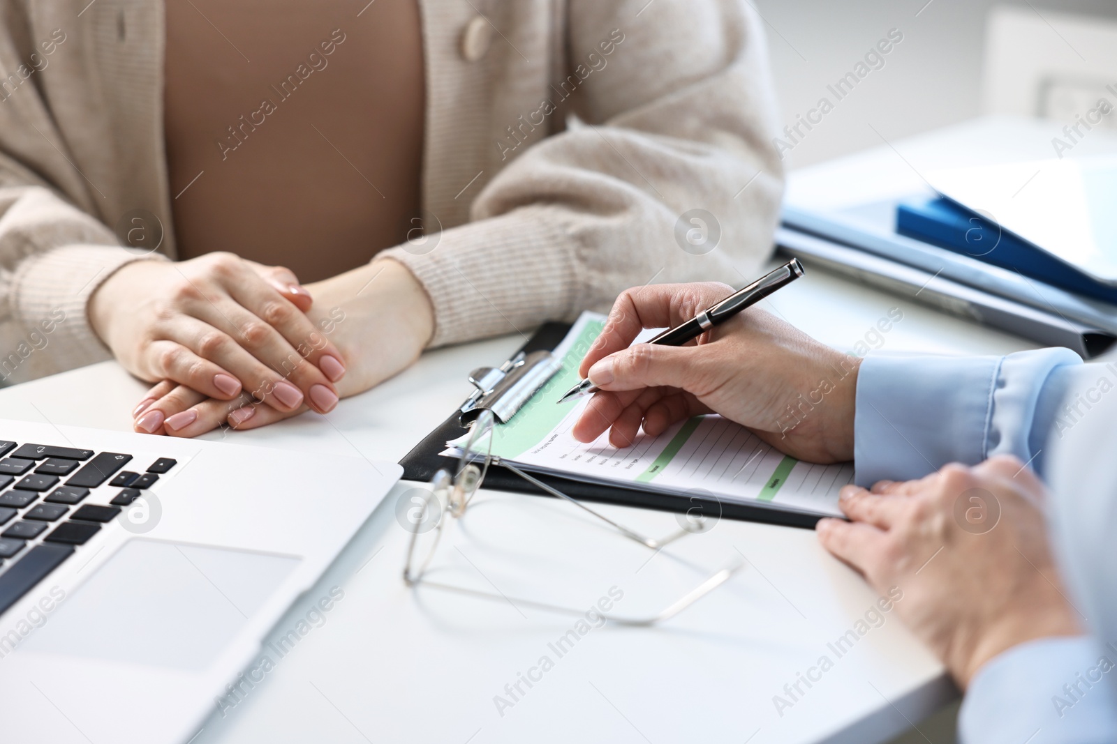 Photo of Professional doctor working with patient at white table in hospital, closeup