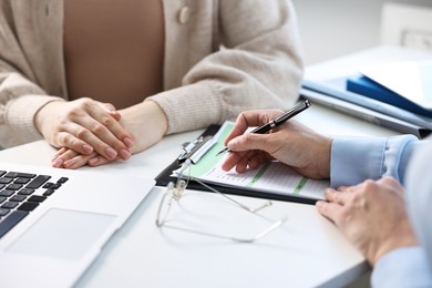 Professional doctor working with patient at white table in hospital, closeup