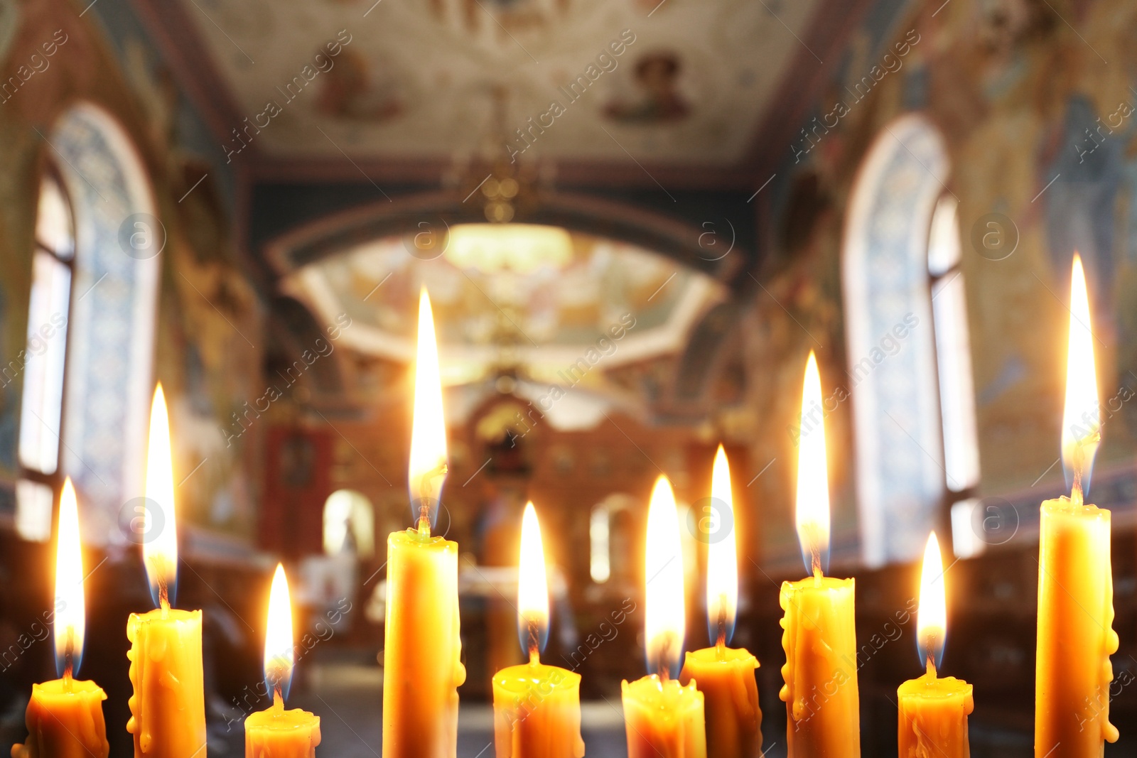 Image of Many church candles burning in temple, closeup