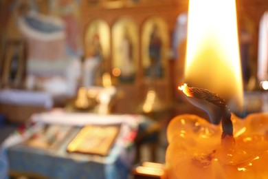 Church candle burning in temple, closeup. Space for text