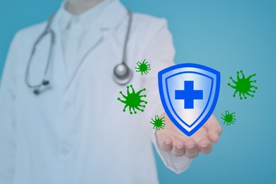 Image of Strong immunity blocking viruses. Doctor holding illustration of shield on light blue background, closeup
