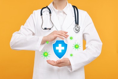 Image of Strong immunity blocking viruses. Doctor holding illustration of shield on orange background, closeup