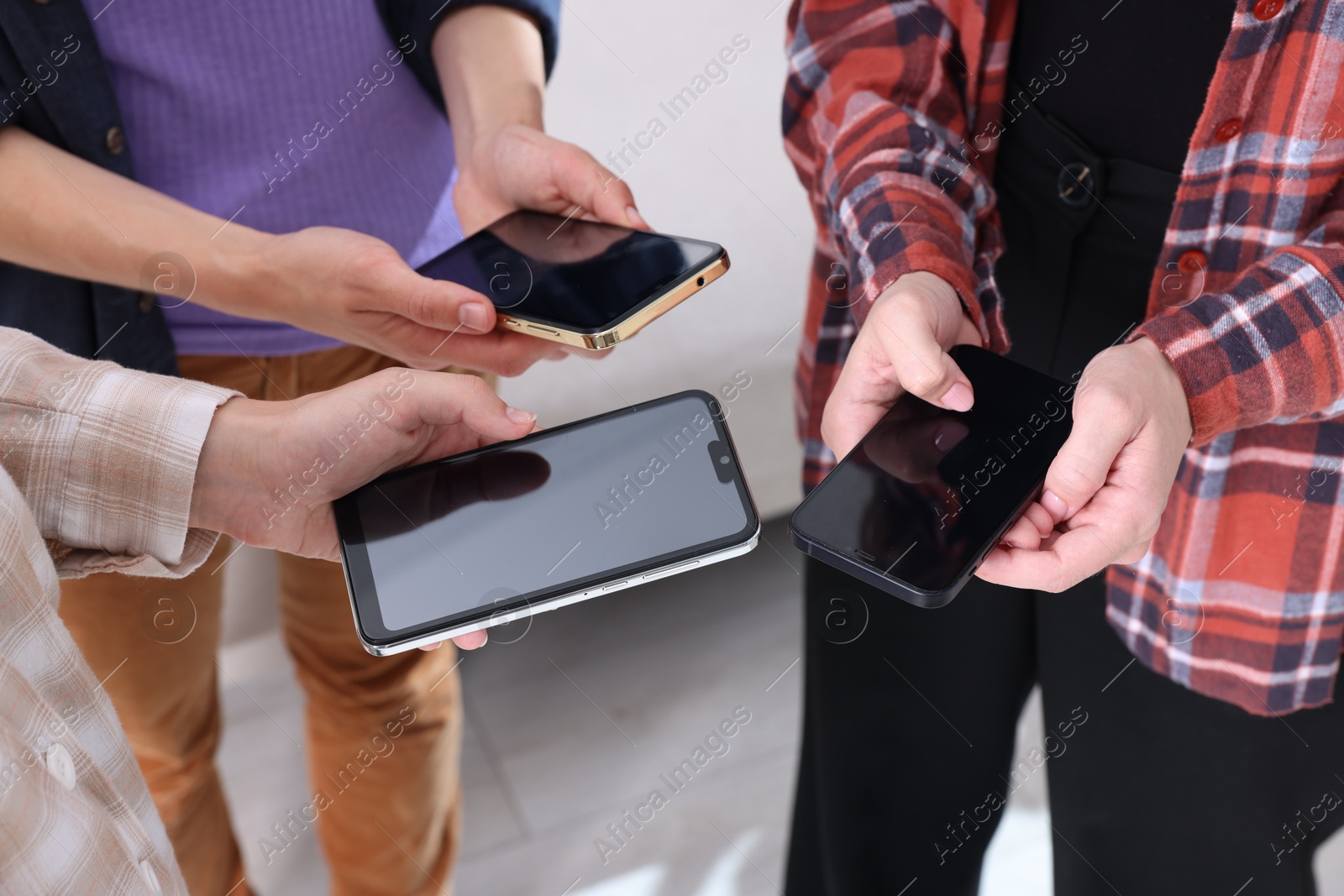 Photo of People holding smartphones with blank screens indoors, closeup