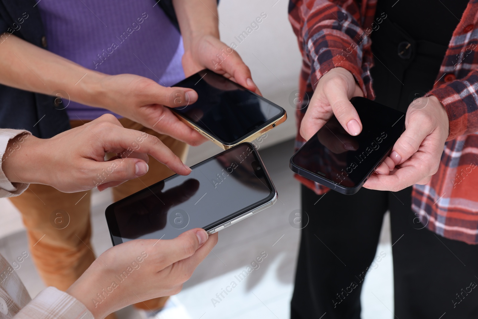 Photo of People holding smartphones with blank screens indoors, closeup