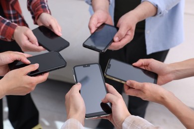 Photo of People holding smartphones with blank screens indoors, closeup