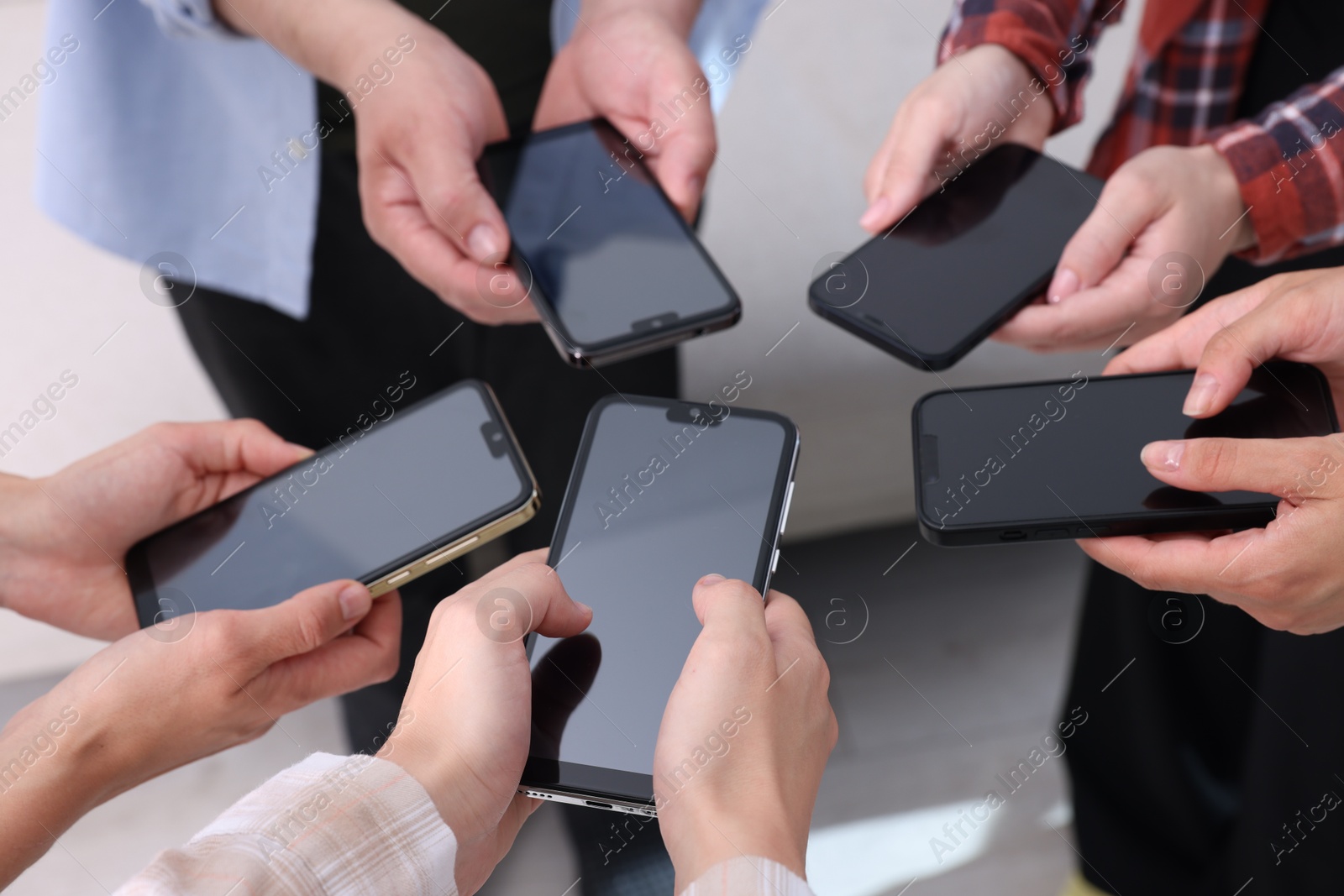 Photo of People holding smartphones with blank screens indoors, closeup