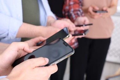 Photo of People holding smartphones with blank screens indoors, closeup