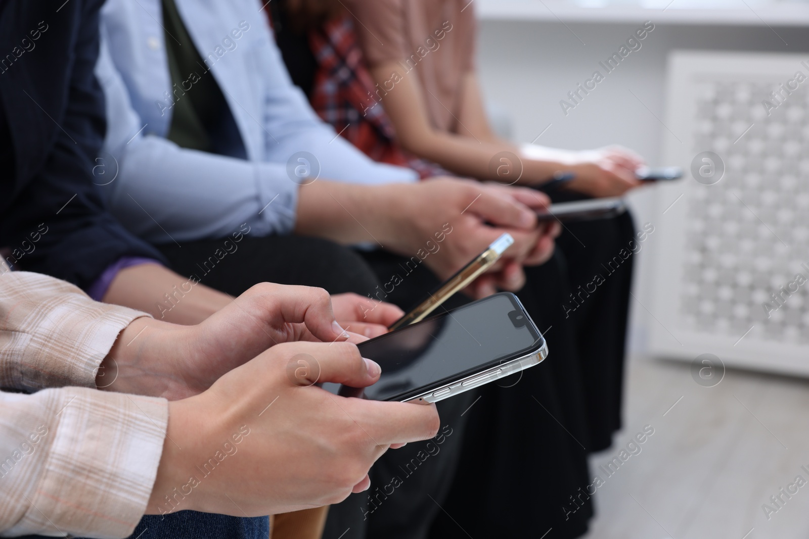 Photo of People holding smartphones with blank screens indoors, closeup