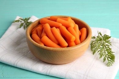 Baby carrots and green leaves on light blue wooden table